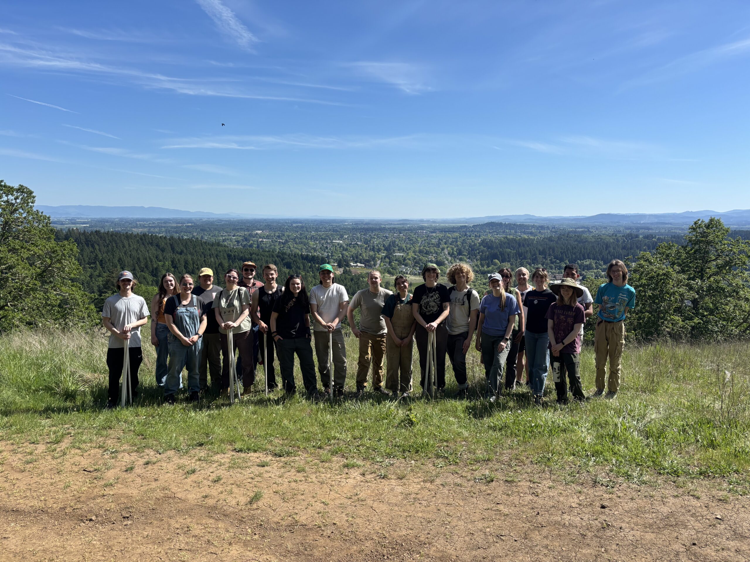 Students gathered outdoors during a field-based class overlooking a forested landscape