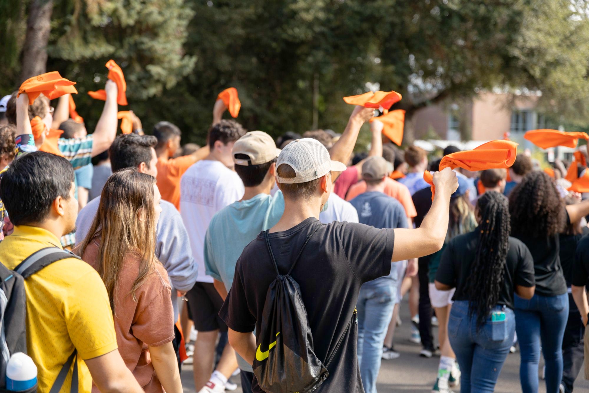 Students holding OSU colored bandanas walk through campus
