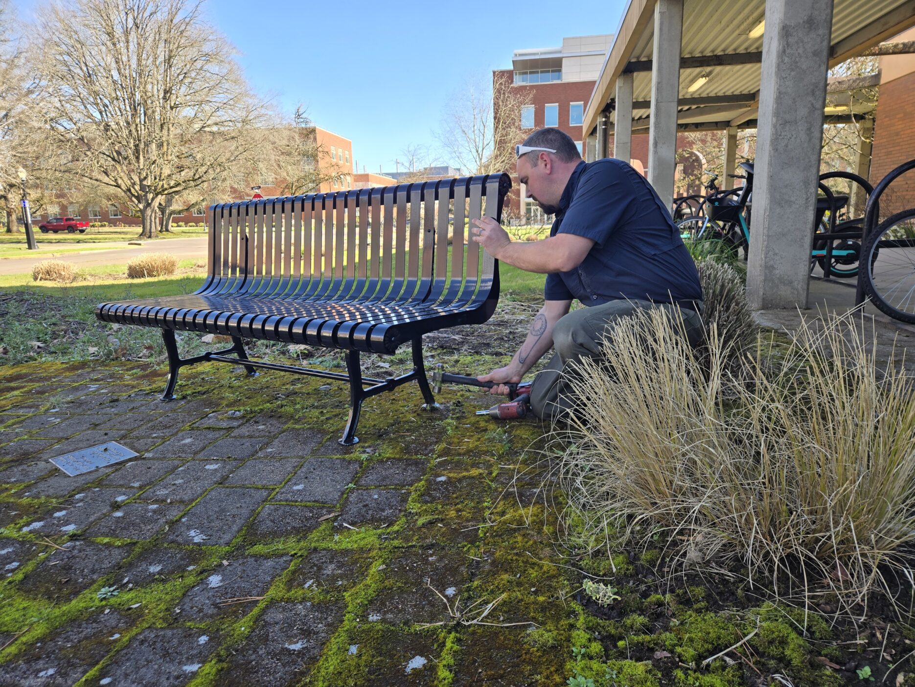 A person installing a metal bench.