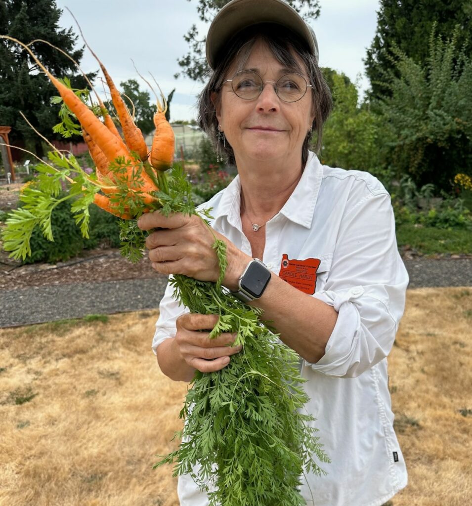 Carole Hardy holding a bunch of carrots.