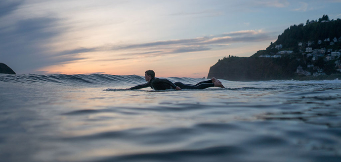 young man paddling out to surf