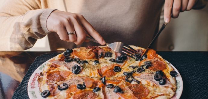 woman cutting into a piece of pizza