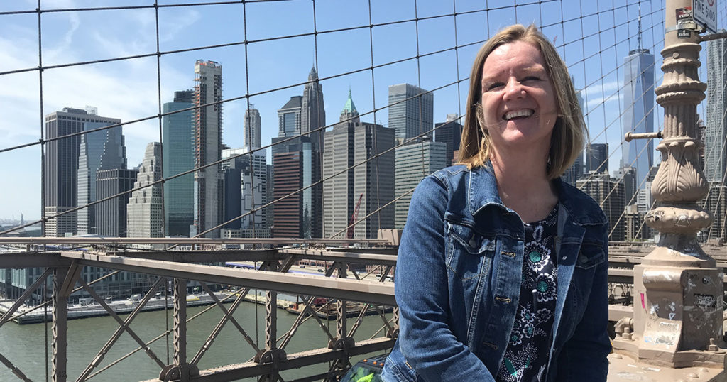 woman poses in front of city skyline