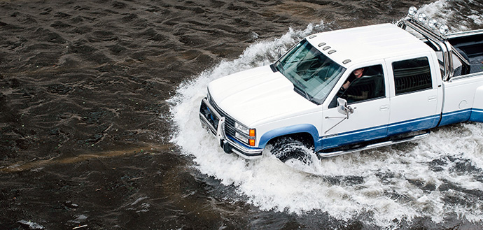 white and blue truck driving in flooded street