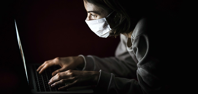 woman in face mask uses a laptop