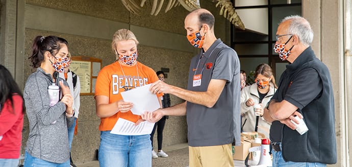 Oregon State scientists and students overview instructions for TRACE project, all wearing masks