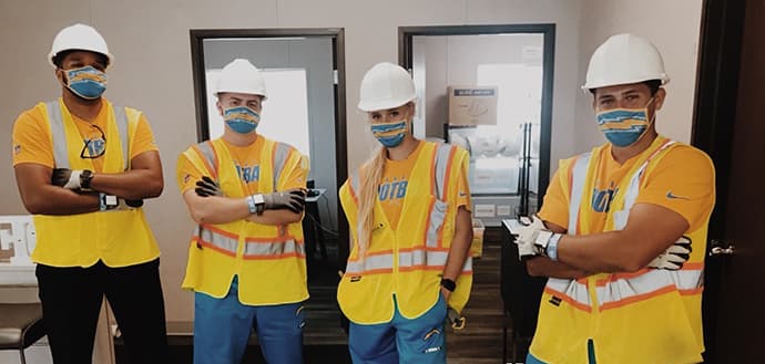 group of NFL athletic training interns wearing hard hats and masks