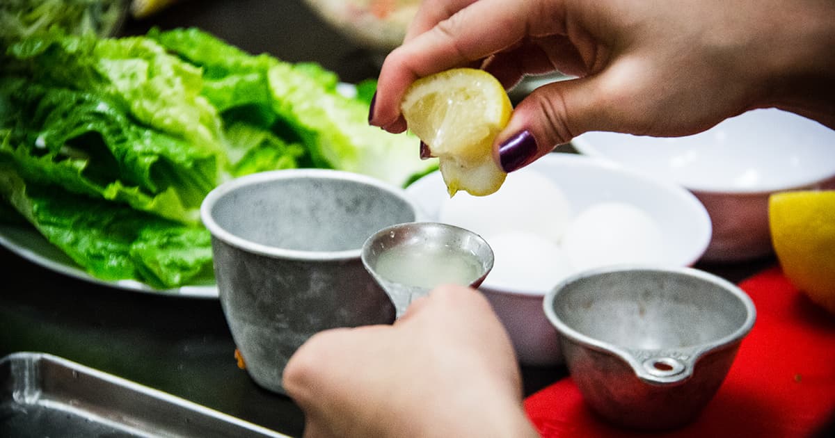 hands squeeze lemon juice into measuring spoon