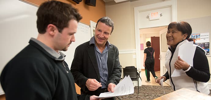 Anthony Veltri looking over papers with male and female students