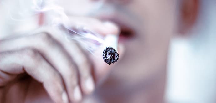 close up of a man smoking a cigarette