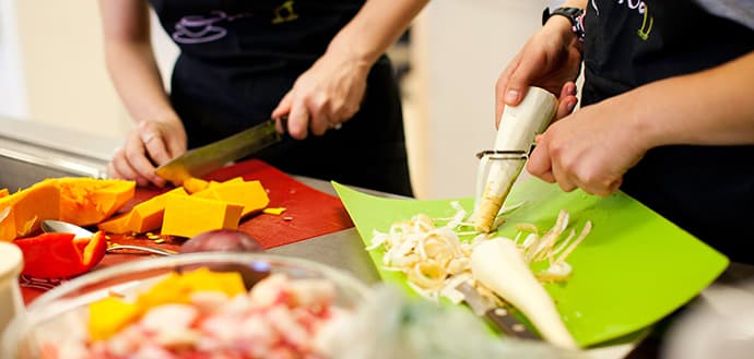 two students chopping and peeling vegetables