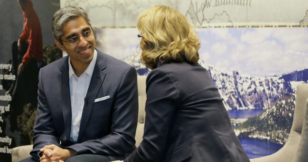 Vivek H. Murthy, MD smiles while sitting and talking to a woman