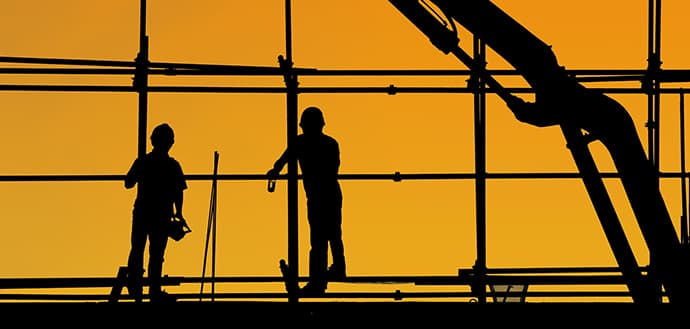 Two silhouetted construction workers with orange background