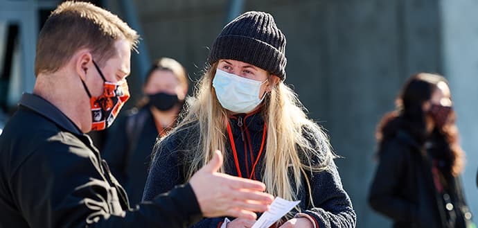 Female wearing mask listens to male wearing a mask and reading off paper