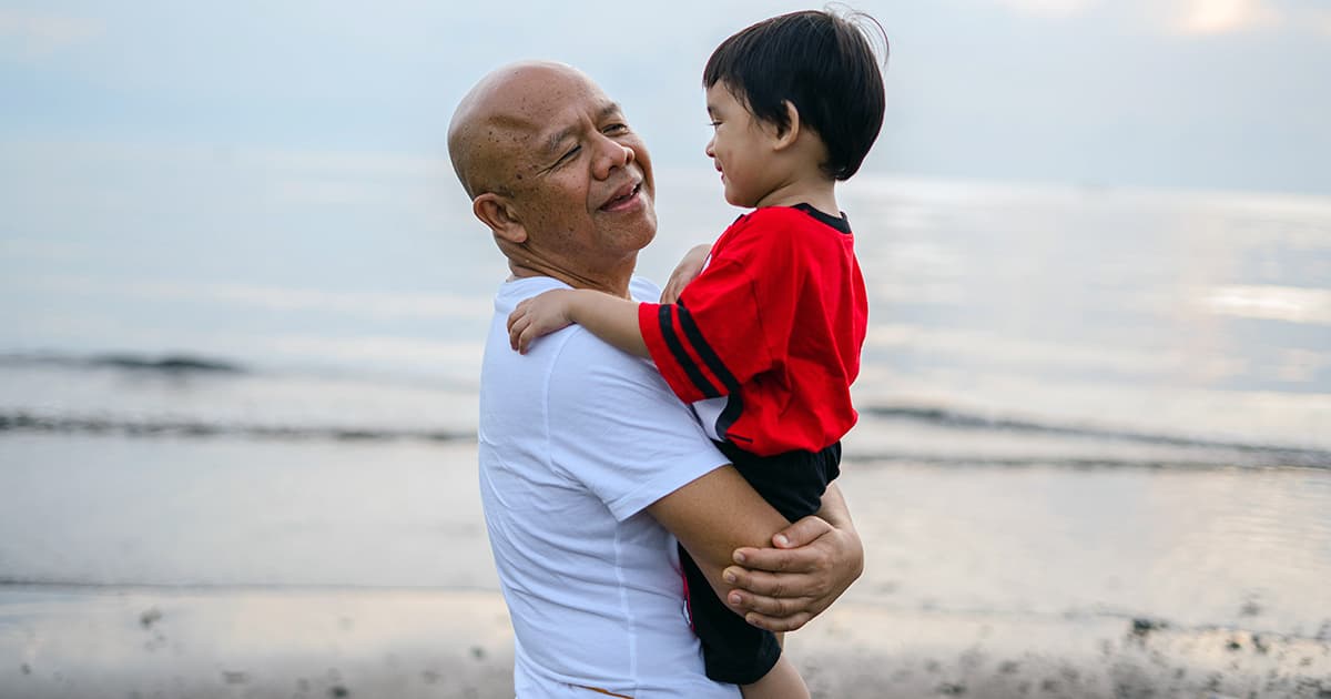 grandparent holds toddler on the beach