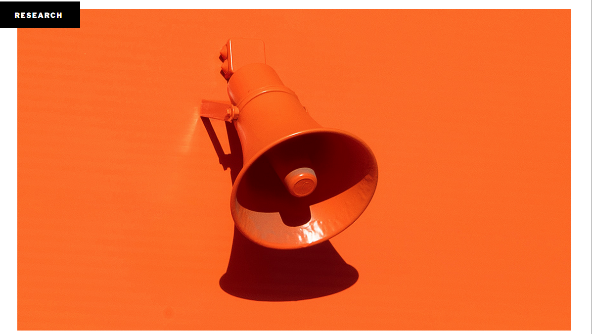 Picture of an orange wall with an orange speaker shaped like a megaphone attached to it