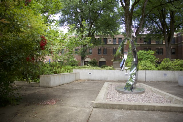 Metal sculpture with many green trees and bushes and concrete platforms for sitting 