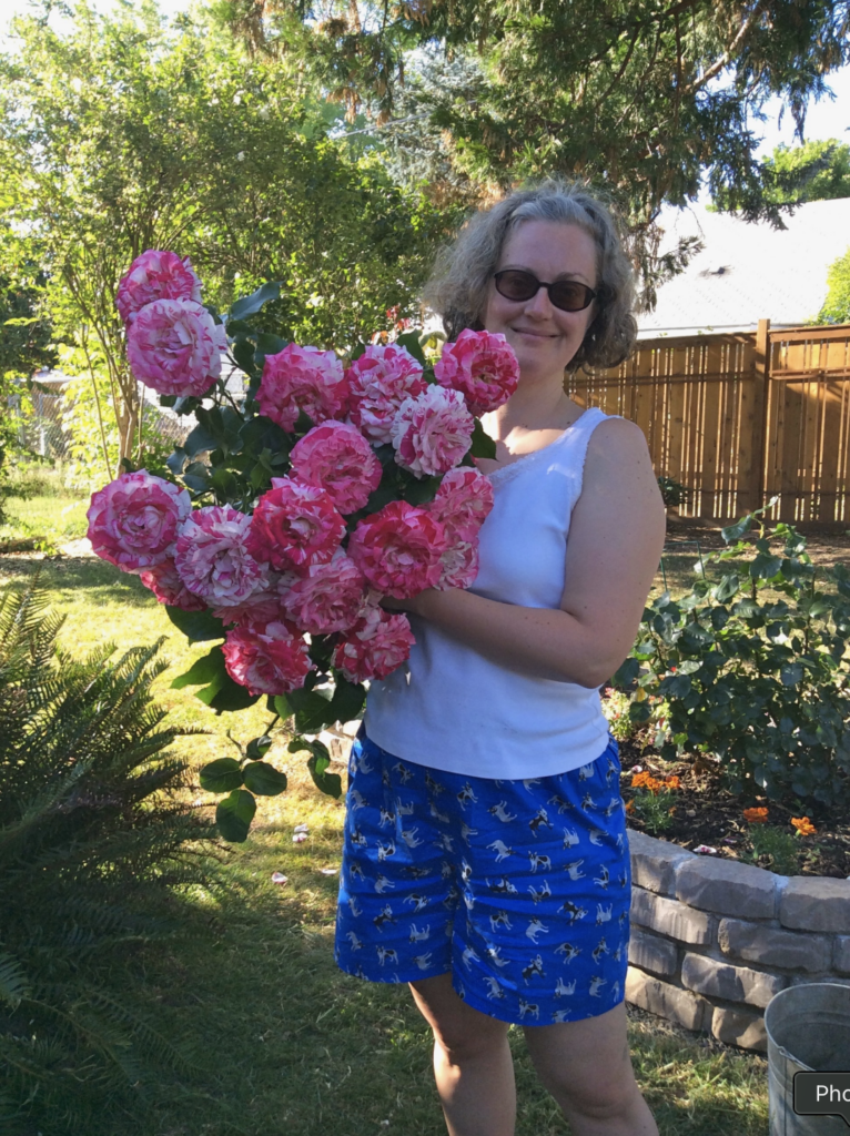 Jean in the garden holding a giant bouquet of mixed red/white roses