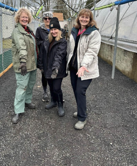 four Master Gardener volunteers outside of greenhouses