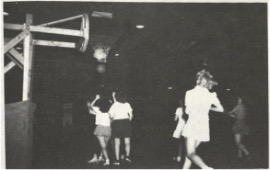 People playing basketball indoors under low lighting.