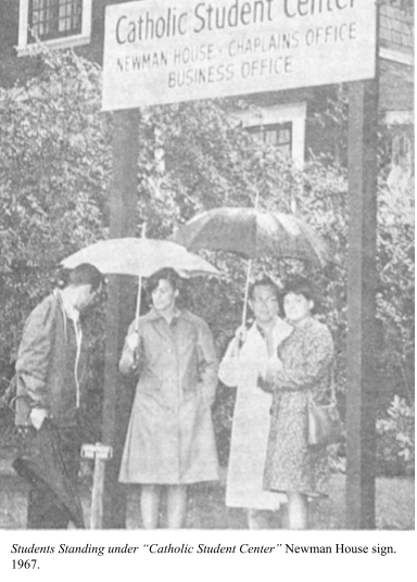 Four white people standing under umbrellas in front of a Catholic Student Center sign, 1967.