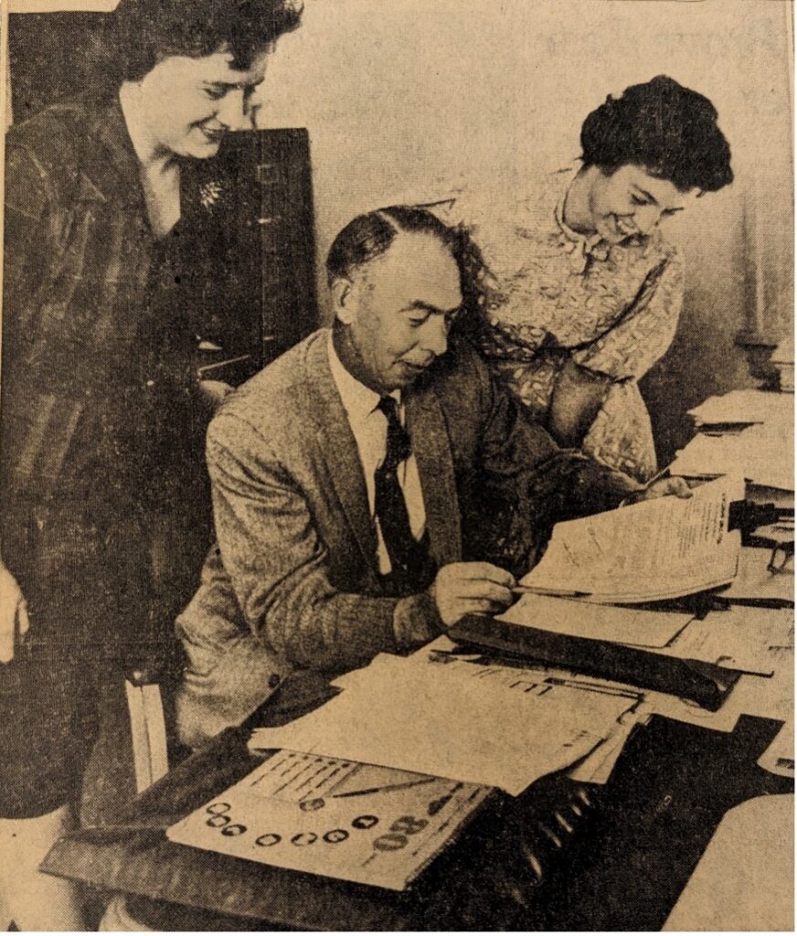 Three white people reviewing documents at an office desk.