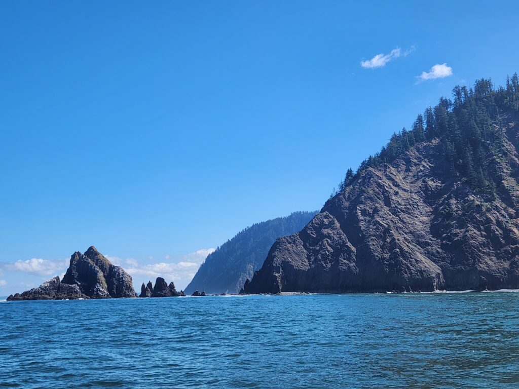 The view from the water of a series of two rocky headlands and some off-shore rocks. 