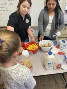 Yolanda Diaz handing out sliced fruit to a little girl for making smoothies.