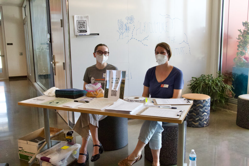 Two women sit at a sign in table for an event.