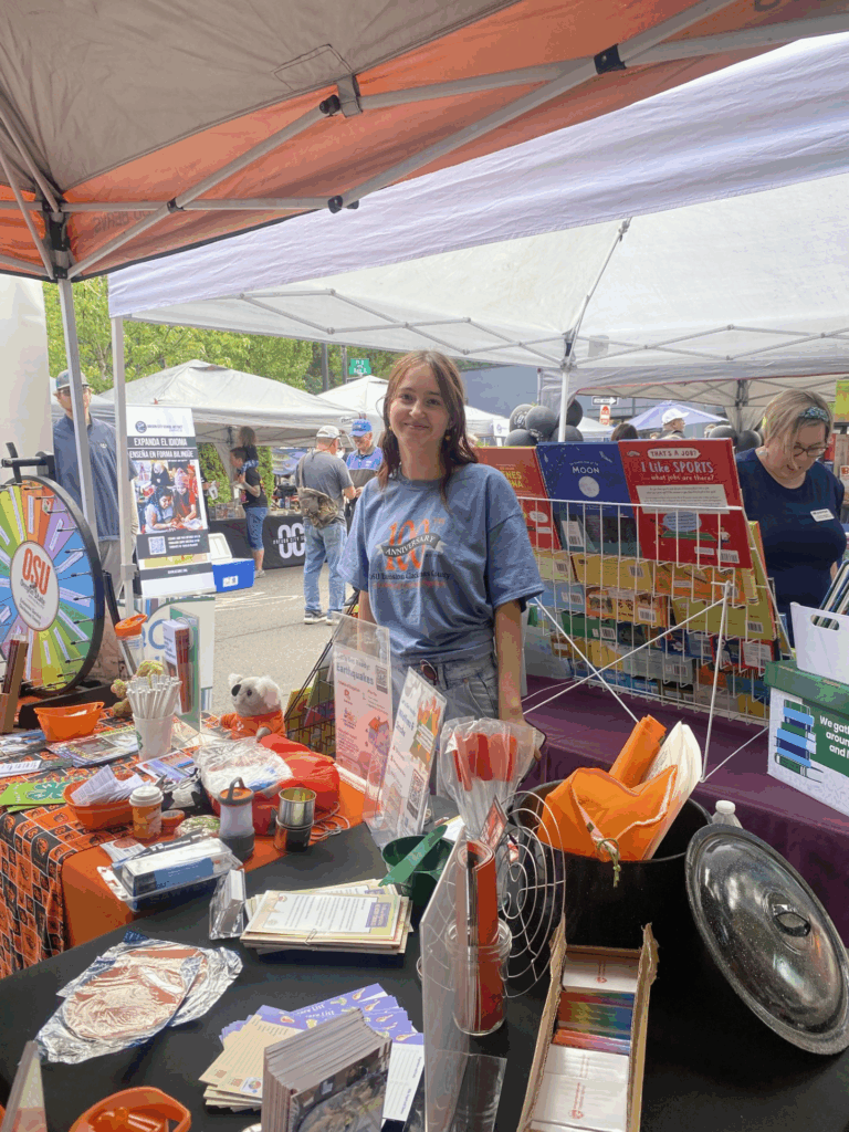 A girl standing behind a booth that has many interactive items and pamphlets
