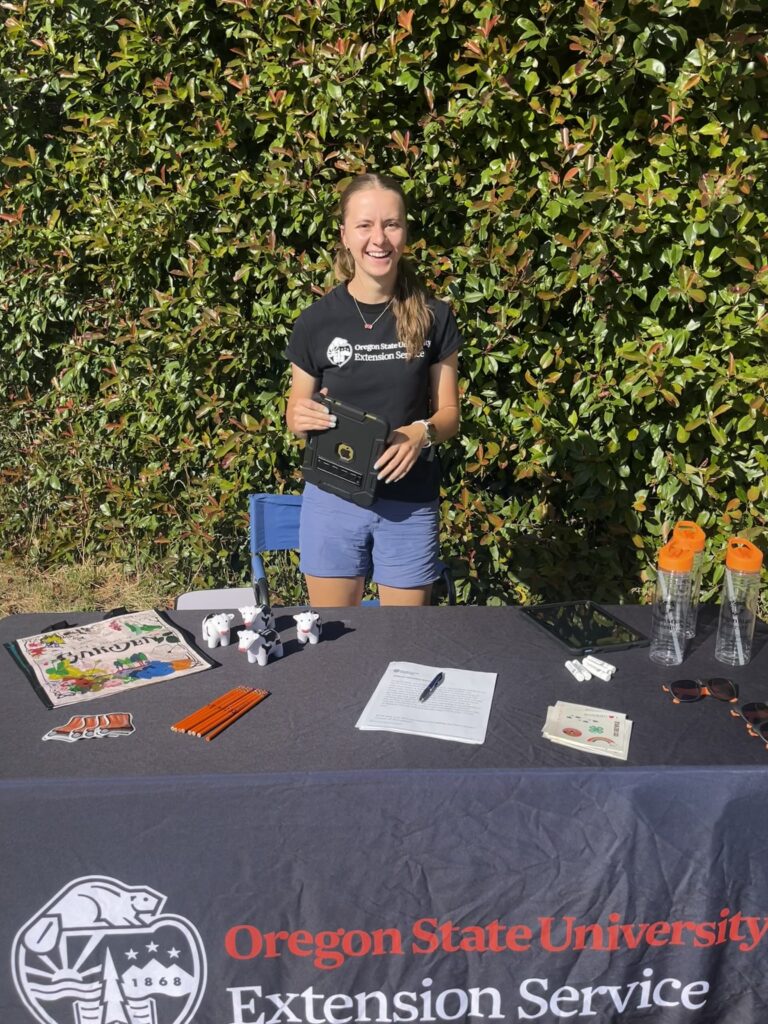 A girl standing behind a table for OSU Extnesion Service with swag on it.