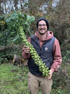 C Taylor holding a stalk of brussel sprouts