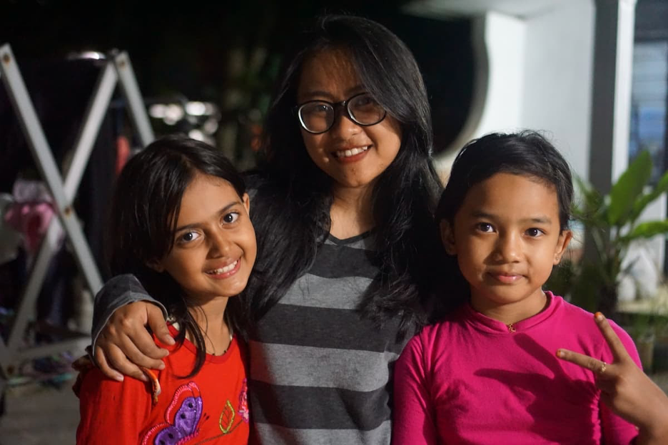 Adult with arms around children.