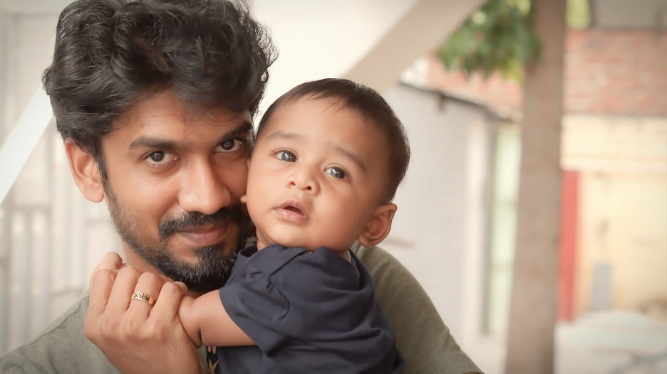 Masculine presenting person holding a baby