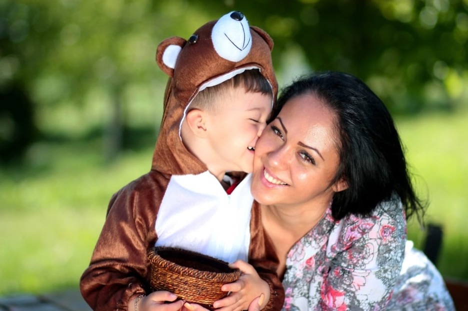 A child wearing a bear costume cuddling with an adult.
