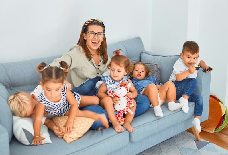 An adult and 5 young children sitting on a couch.