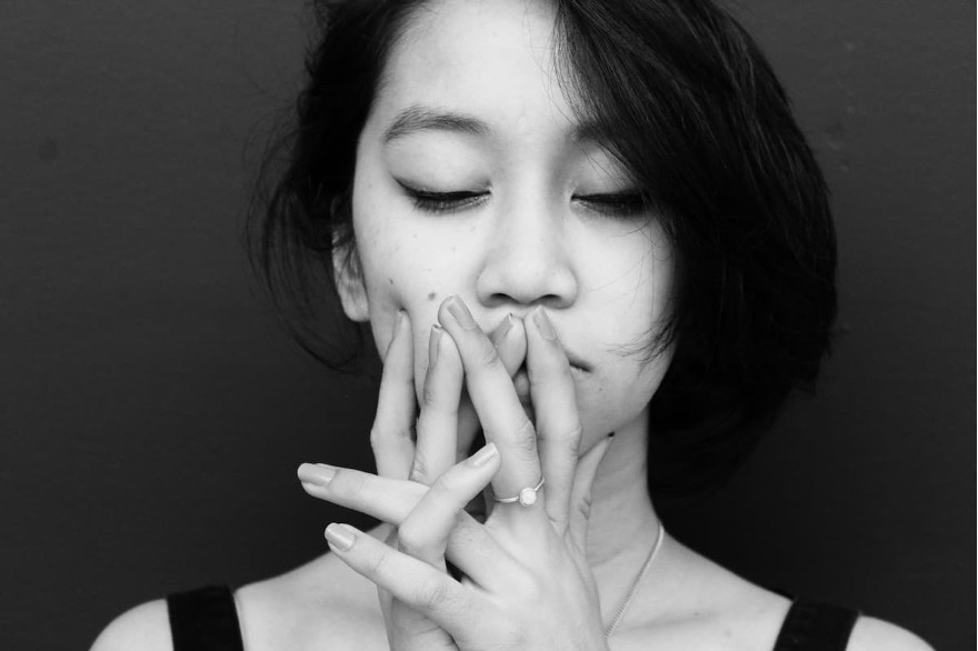 A portrait of a person with their hands on their face