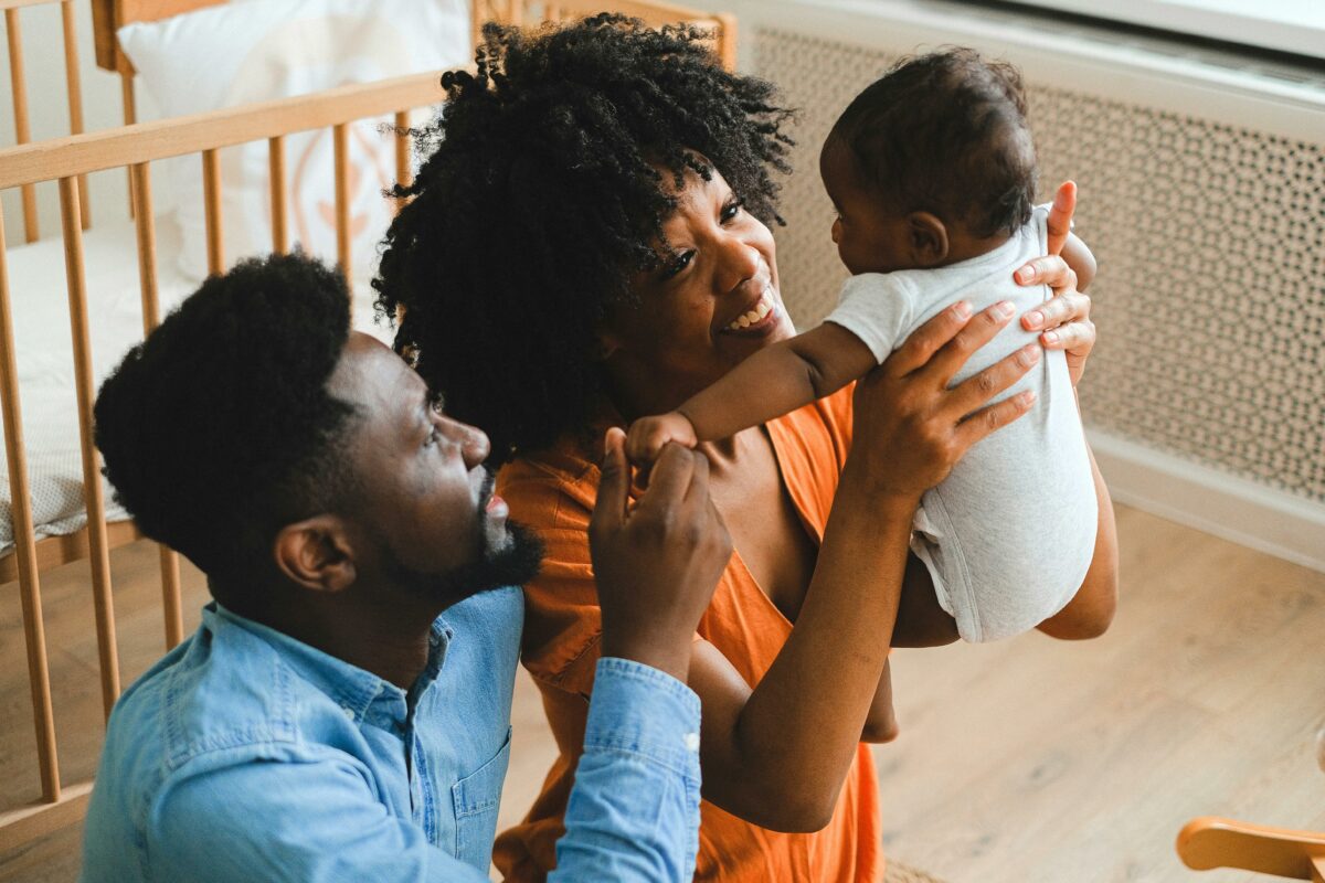 Two parents smile at a young baby