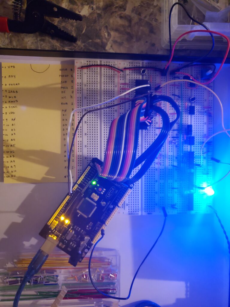 Arduino MEGA connected to the address and data ports of the 6502 processor with clock, R/W, and ground -- output printing each clock cycle what each of the pins are seeing within the Serial Monitor on the Arduino software (not shown here)