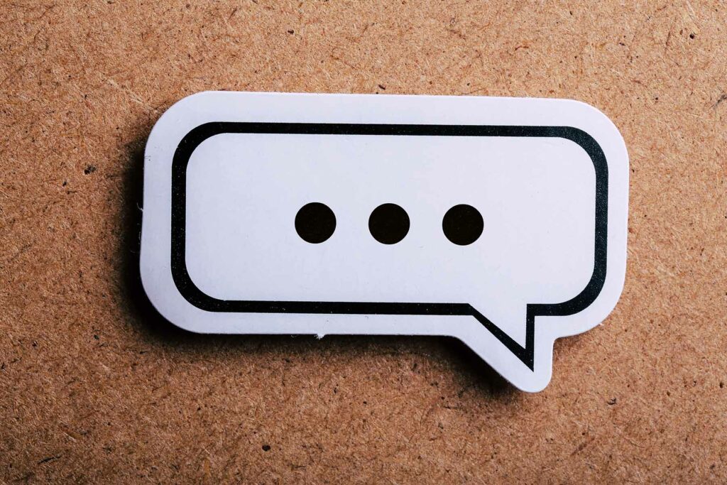 speech bubble with no words, just three dots, placed on a corkboard background