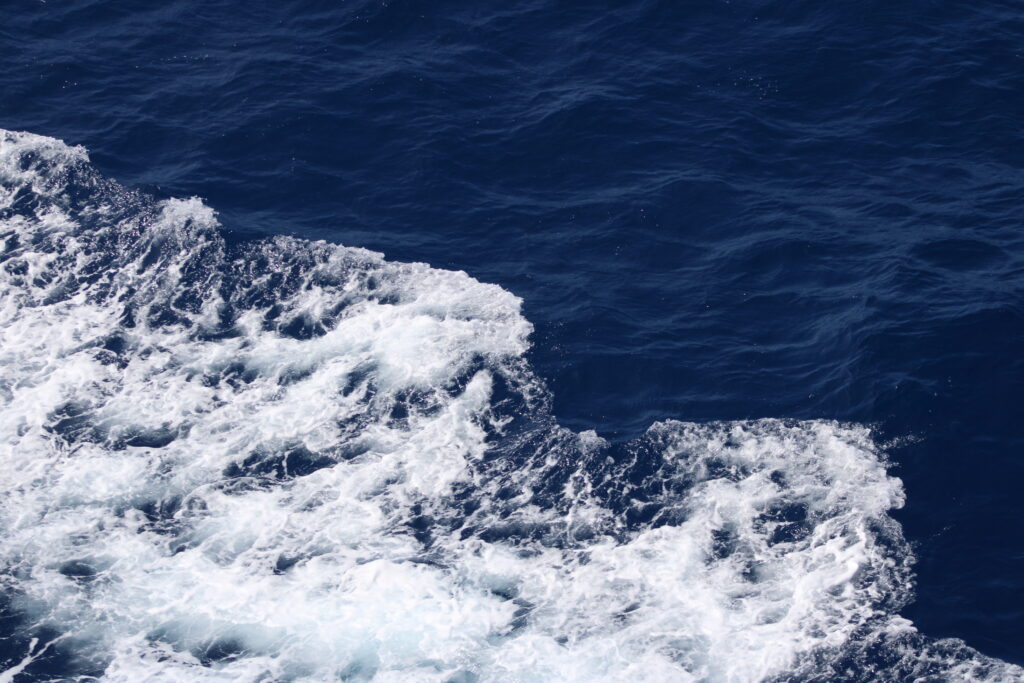 White waves from a boat on deep blue water.