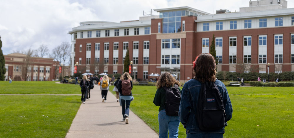 Students walking on the sidewalk towards the library at Oregon State University